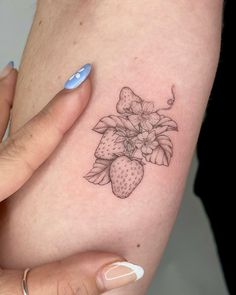 a woman's arm with a flower and strawberry tattoo on the left side of her body