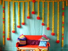 an orange couch sitting in front of a wall with pom poms on it