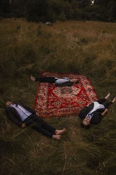 two people laying on a rug in the middle of a field with their heads together