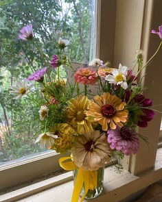 a vase filled with lots of colorful flowers sitting on top of a window sill