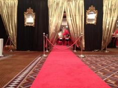 a red carpet is on the ground in front of black curtains and gold drapes