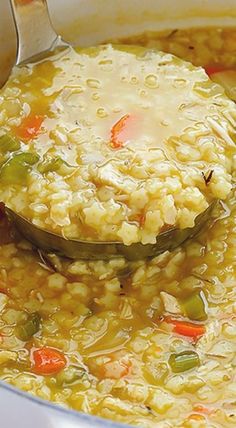 a ladle full of soup with rice and vegetables