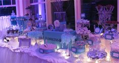 a table topped with lots of desserts and candies covered in frosting next to a window