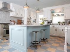 a kitchen with two stools in front of the island and white cabinets on both sides