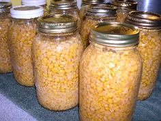 several jars filled with food sitting on top of a counter next to each other and the words canning corn in front of them