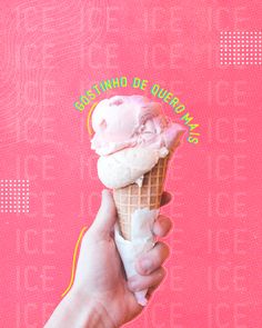 a hand holding an ice cream cone with pink icing