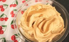 a glass bowl filled with peanut butter on top of a floral tablecloth covered table