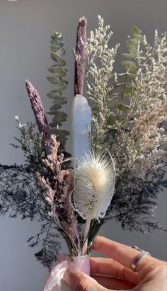 a person is holding a flower arrangement in their hand