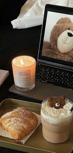 a laptop computer sitting on top of a desk next to a cup of coffee and pastry