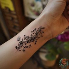 a tattoo with musical notes on it's arm and the word music written in cursive letters