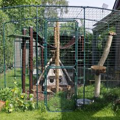 an animal cage with various animals in it on the grass near a building and trees