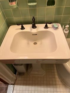 a white sink sitting under a bathroom mirror next to a bathtub and toilet paper dispenser