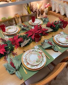 the table is set for christmas dinner with poinsettis and greenery on it