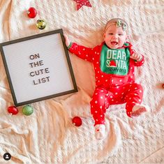 a baby laying on top of a bed next to a sign that says dear santa