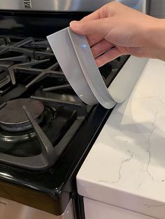 a person is opening the door to an oven with a paper holder on top of it