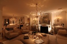 a living room filled with lots of furniture and a chandelier hanging from the ceiling