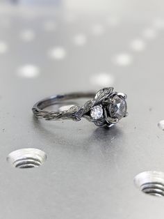 a diamond ring sitting on top of a silver surface with white dots around the edges