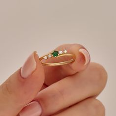 a woman's hand holding an emerald and diamond ring