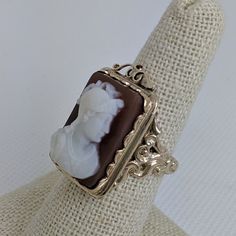 This gorgeous vintage cameo ring is beautifully crafted in a solid 14k gold frame with details at every angle. The victorian style is likely a 1930-1950s creation. In the center is a carved shell cameo of a Roman soldier. The cameo is in excellent condition and the sturdy ring measures approximately 26.45mm tall (including gold filigree fame) x 17.37mm wide. The ring is currently a ring size 7.5 but can be resized by your trusted local jeweler. A bold statement ring for men and women who love an Vintage 14k Gold Cameo Rings, Antique Cameo Ring Collectible, Vintage Carved Signet Ring For Formal Occasions, Art Deco Cameo Ring For Collectors, Art Deco Cameo Ring Collectible, Art Deco Cameo Collectible Rings, Antique Carved Collectible Ring, Vintage Cameo Signet Ring, Vintage 14k Gold Carved Ring