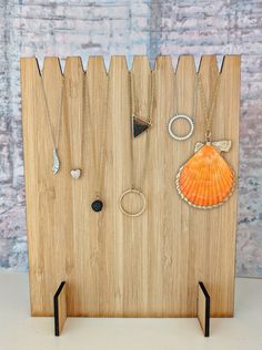 a wooden board with various necklaces and rings on it