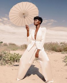 a woman in white is holding an umbrella over her head and posing for the camera