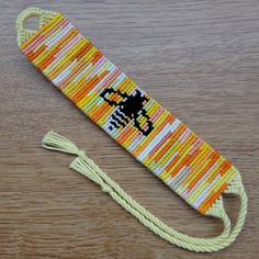 an orange, yellow and white beaded lanyard with a black cat on it