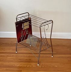 a metal magazine rack with an album on it's side and a vinyl record in the middle