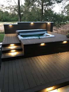 a hot tub sitting on top of a wooden deck next to a fire pit with lights around it