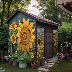 a garden shed with sunflowers painted on it's side and two bicycles parked next to it