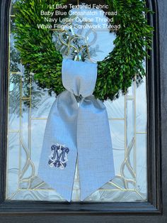 a wreath with the letter m on it in front of a glass door that says baby blue