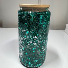 a glass jar with blue and green speckles sitting on top of a white table