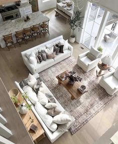 an aerial view of a living room with white furniture and large windows overlooking the kitchen