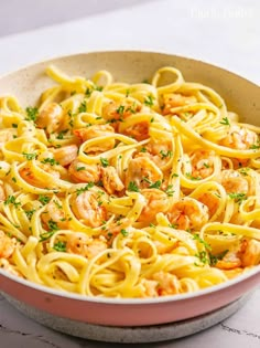 a bowl filled with pasta and shrimp on top of a table