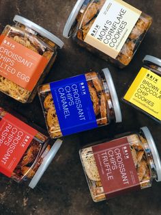 six jars of food sitting on top of a table next to each other with different labels