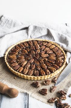 a pecan pie sitting on top of a table next to a knife