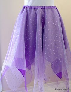 a purple and white dress with stars on the skirt is displayed in front of a mannequin