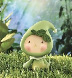 a small figurine sitting in the grass with leaves on it's head