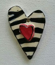 a black and white striped heart with a red heart on it's side hanging from a wall