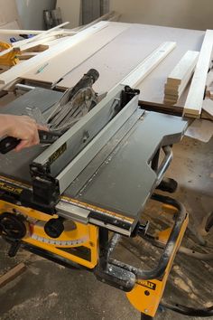 a person using a table saw to cut plywood planks with a machine in the background