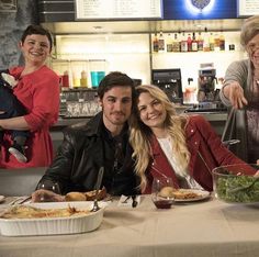 a group of people sitting at a table with food and drinks in front of them