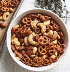 a white bowl filled with nuts and pretzels