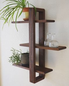 a wooden shelf with two plants on it and a potted plant in the corner