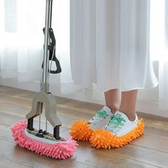 a pair of feet in white shoes with pink and orange duster on the floor