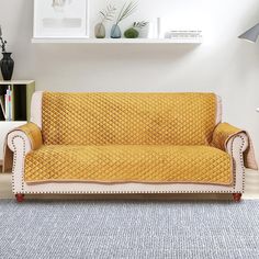 a yellow couch sitting on top of a wooden floor next to a white book shelf