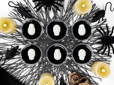 halloween candles are arranged in the shape of a spider's web with black and white decorations