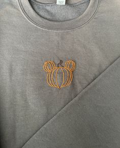 a gray shirt with an orange mickey mouse embroidered on it