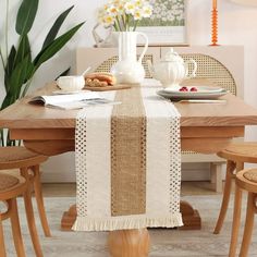 a dining room table set with place settings and flowers in vases on the table