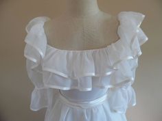 "Vintage 1990s Redux 1950s Short Sleeved; Ruffle Trimmed Wedding Gown, Dress with Full Skirt by Paris Design House, Sasson. This dress is made from a fine white organza and boasts a double satin trimmed ruffle, (top is 4 inches, bottom is 5.5 inches,) on an off-shoulder neckline. The puff sleeves are cinched part way down and have satin trim as well. It has a fitted bodice accented by a satin (attached) belt that buttons in the back with two buttons and elastic loops that have oxidized and need Vintage Ruffled Dress For Debutante Ball, Vintage Victorian Dress With Ruffles For Debutante Ball, White Regency Style Petticoat With Ruffles, Vintage White Ruffled Wedding Dress, Vintage Wedding Dress With Ruffled Skirt, Formal White Gown With Ruffles, Fitted Regency Gown With Ruffles, Fitted Ruffled Gown For Vintage Events, Regency Style Formal Gown With Ruffles