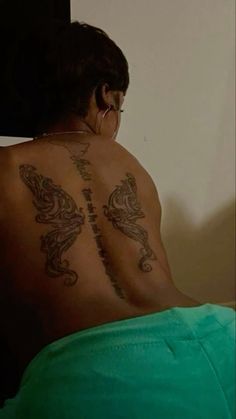 a woman with tattoos on her back sitting down