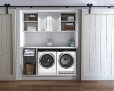 a washer and dryer in a room with white walls, wood floors and open shelving